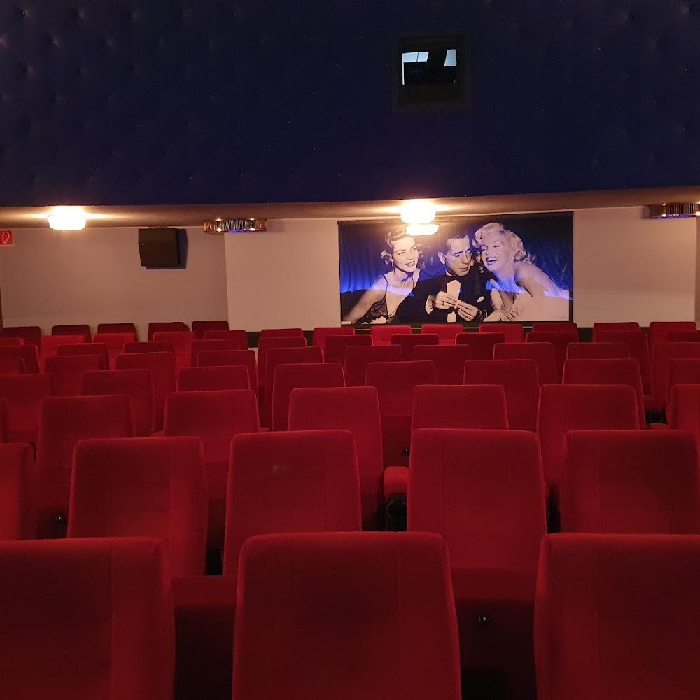 Red cinema seats in front of a movie poster.